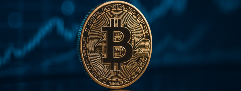 Golden Bitcoin coin in front of blue financial chart background